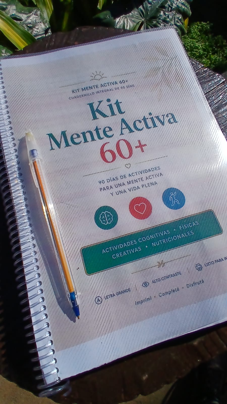 El Kit Mente Activa 60+ ya impreso y anillado, con una lapicera lista para usar, fotografiado al aire libre